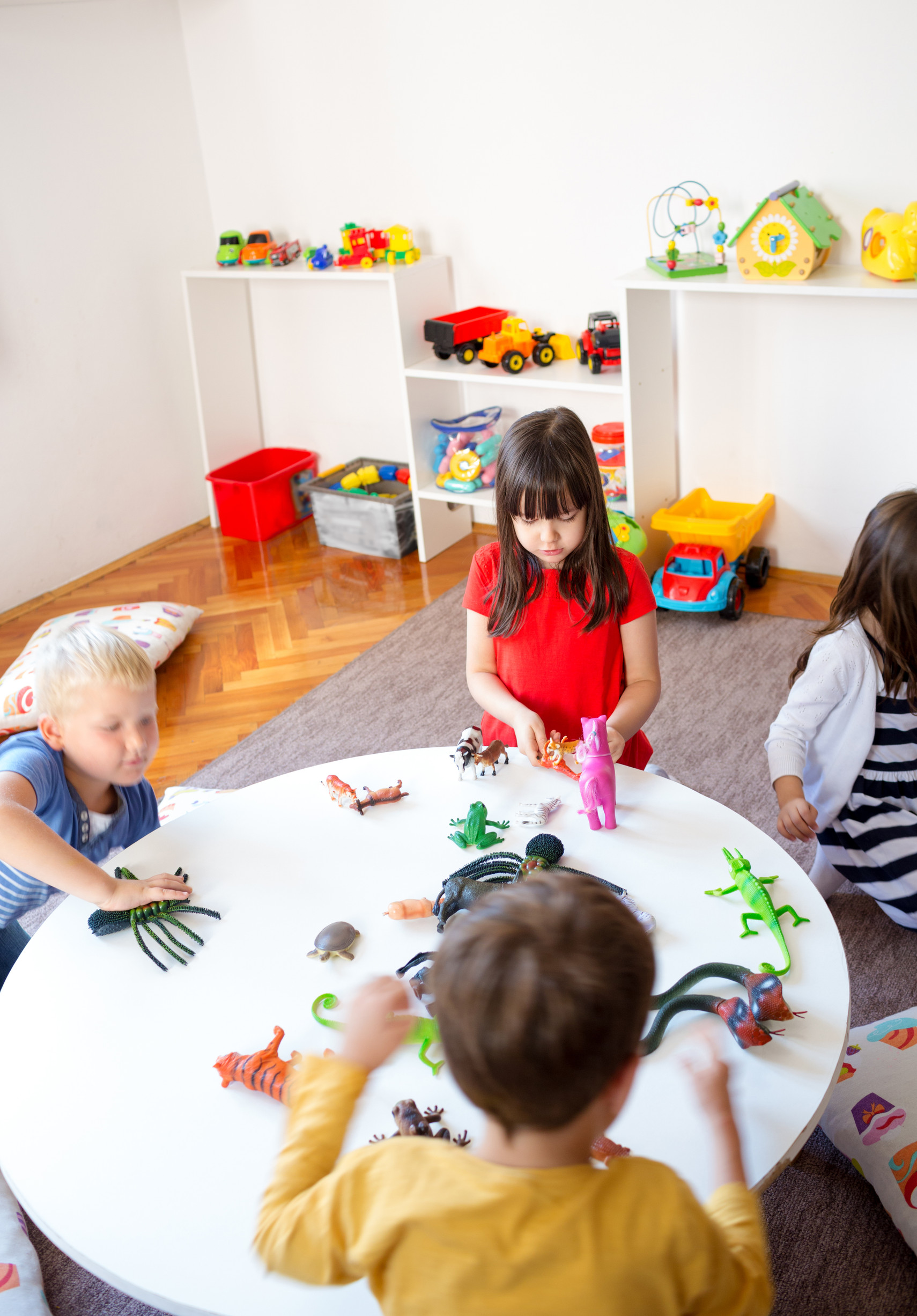 A group of children playing with animal toys in kindergarten